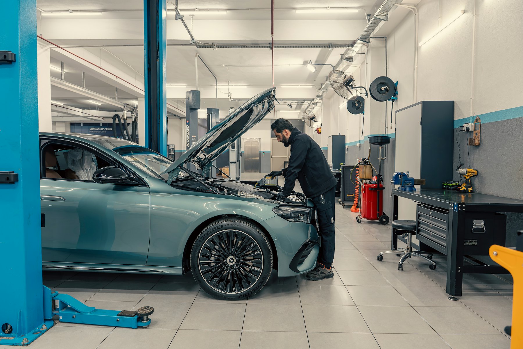 Mechanik przy silniku auta na podnośniku w jasnym warsztacie